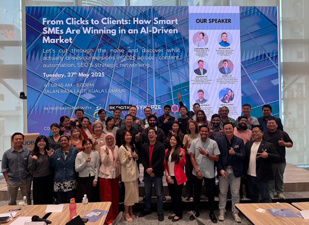 Group photograph of workshop participants in front of an event backdrop